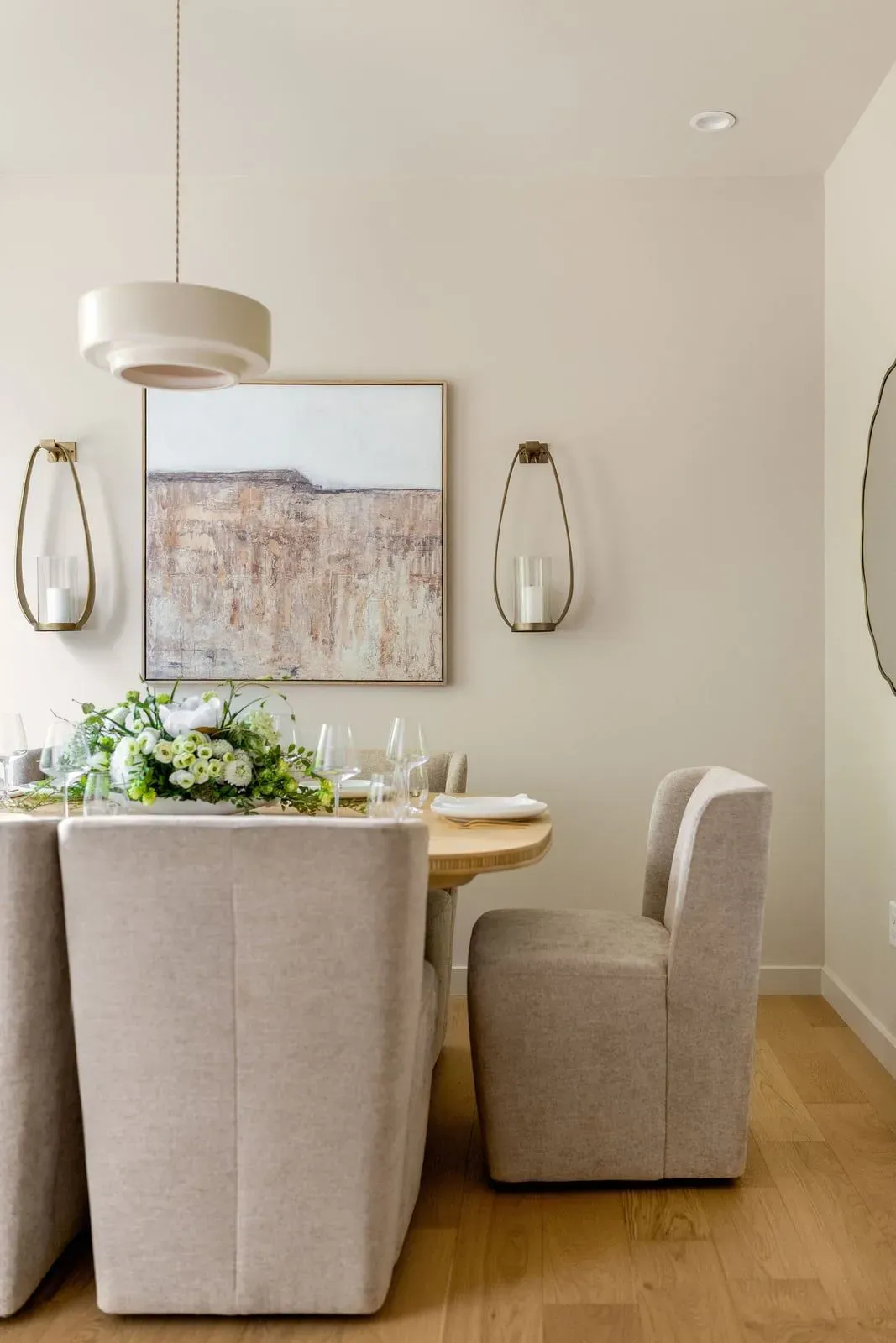 Set dining table with white florals, upholstered chairs, and a gold-framed painting