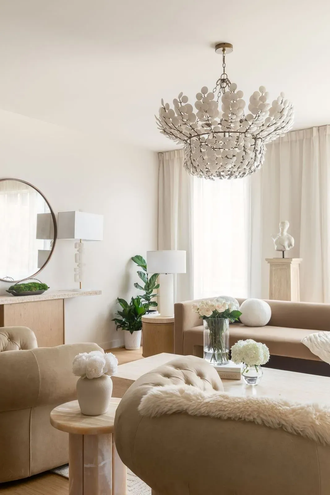 Living room with tufted chairs, a wood coffee table, and a sculptural white chandelier