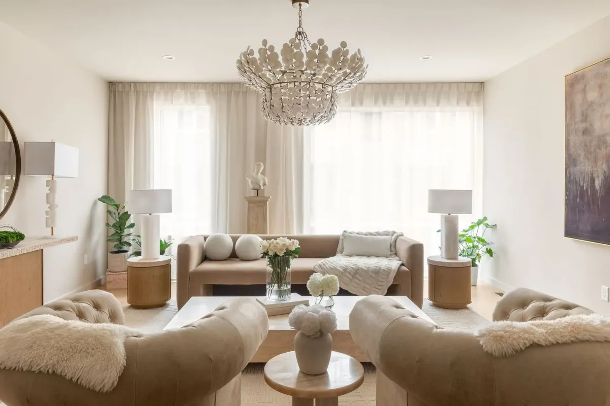 Bright living room with a tan sofa, sheer curtains, and a chandelier of white discs